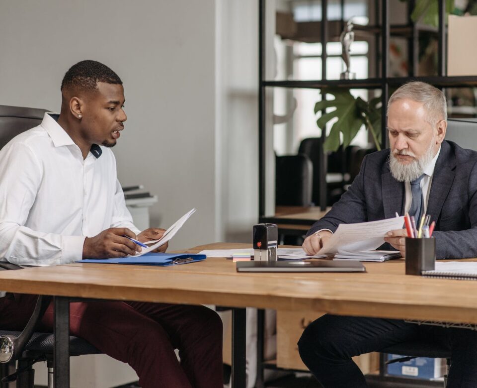 Man in White Dress Shirt Sitting Beside Man in Red Long Sleeve Shirt