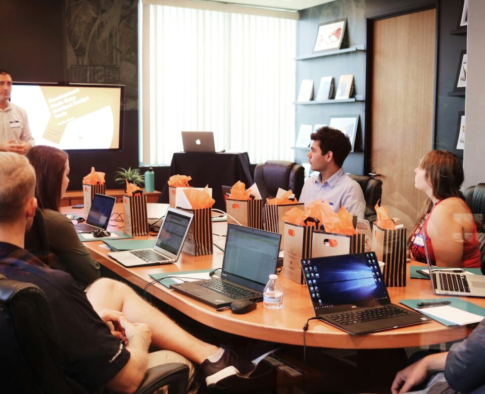 man standing in front of people sitting beside table with laptop computers